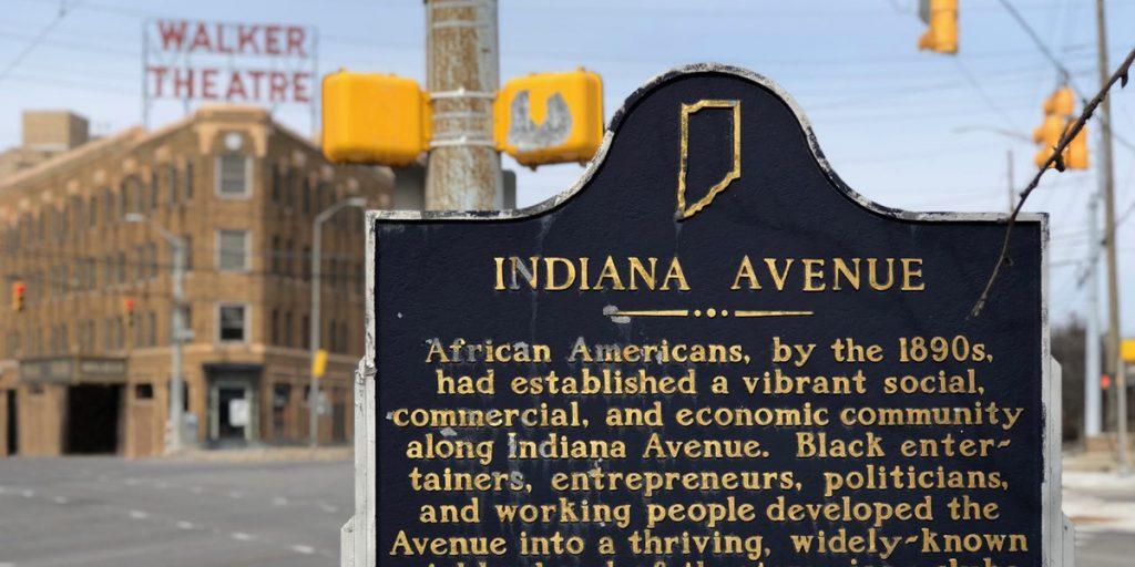 alt="The Walker Theatre and the Indiana Avenue historical marker which begins with 'African Americans, by the 1890s had established a vibrant social, commercial, and economic community along Indiana Avenue. Black entertainers, entrepreneurs, politicians, and working people developed the Avenue into a thiving, widely-known...'"